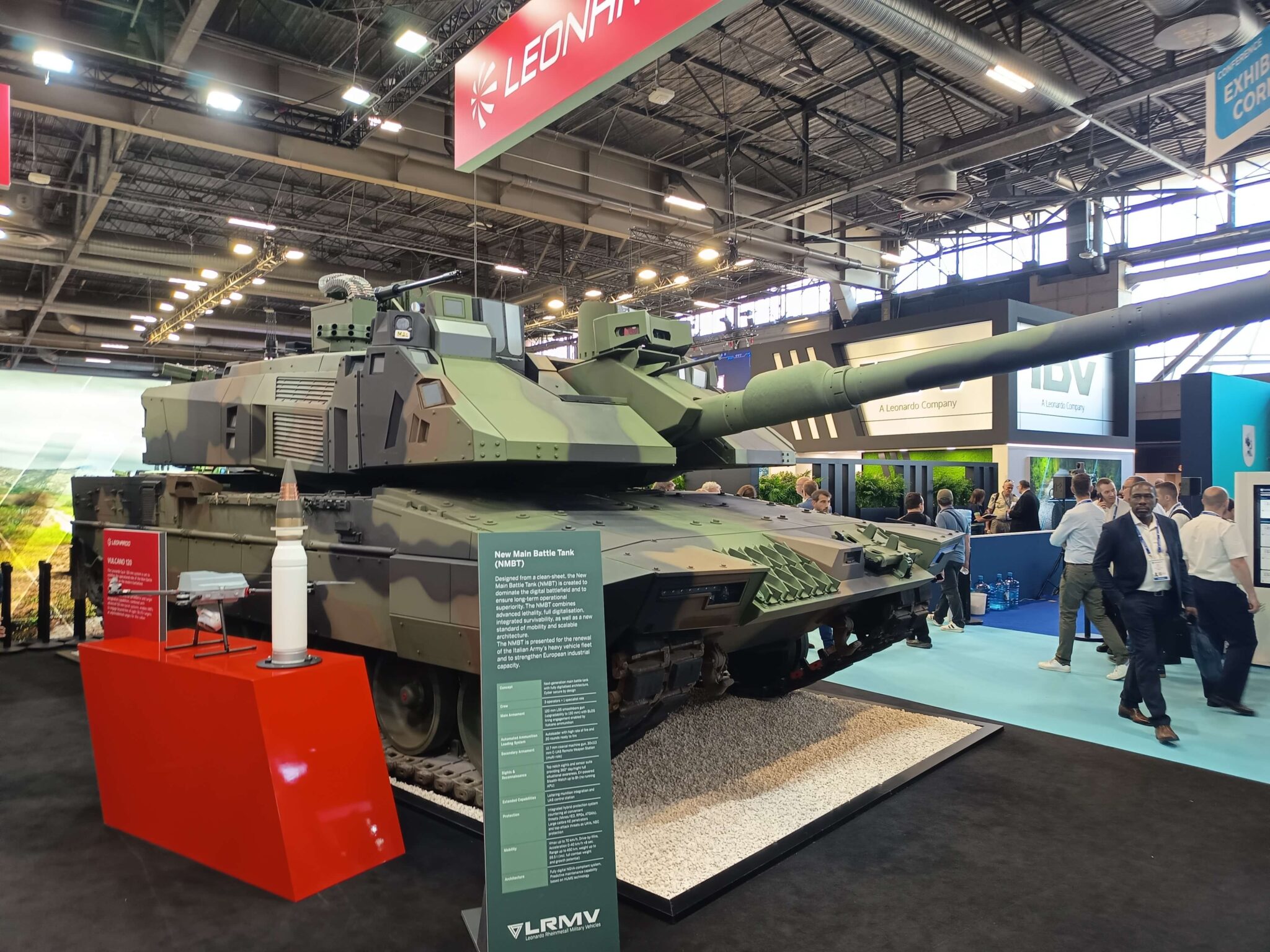 Char NMBT de LRMV vu de trois quarts sur le stand Leonardo à Eurosatory 2026, avec sa fiche technique et un obus Vulcano de 120 mm au premier plan