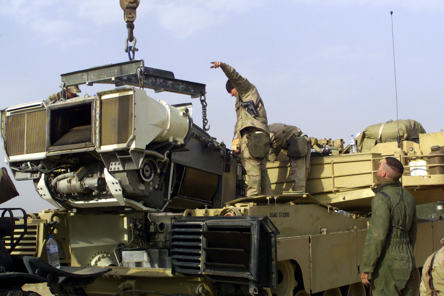 Des Marines du 1er bataillon de chars remontent une turbine AGT1500 dans un M1A1 Abrams, au camp Coyote au Koweït, en février 2003. Photo : Sgt Paul L. Anstine II, USMC / Domaine public