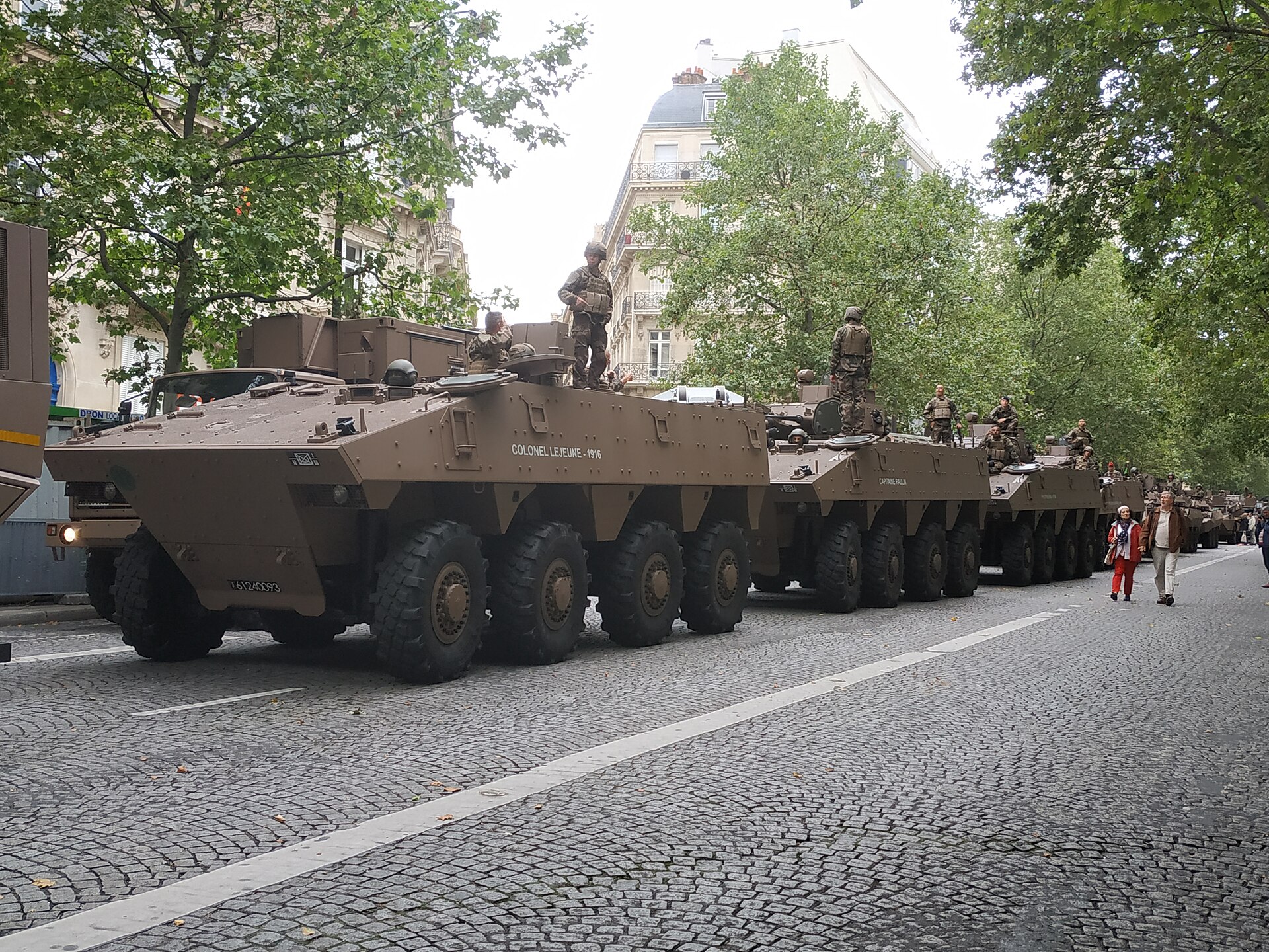 Colonne de véhicules blindés de combat d’infanterie français en livrée sable dans une rue pavée de Paris