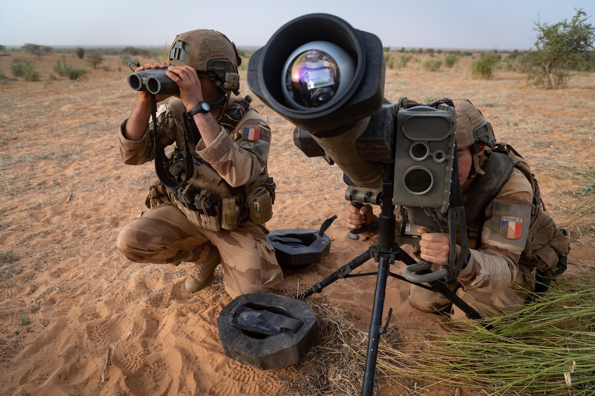 Deux soldats français en tenue désert déploient un missile Akeron MP sur trépied au Sahel, l’un observant aux jumelles Vector 21