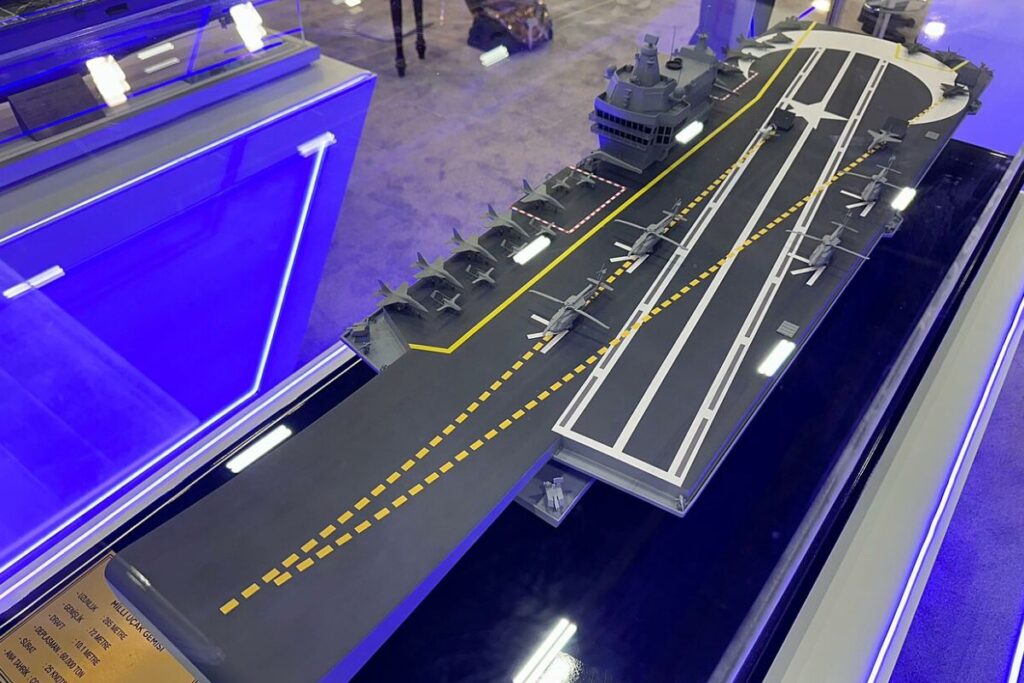 Le MUGEM doit devenir le premier véritable porte-avions conçu et construit en Turquie. Mis en chantier en janvier 2025 à l’arsenal naval d’Istanbul, il est prévu avec un déplacement supérieur à 60 000 tonnes, une vitesse de plus de 25 nœuds et un groupe aérien mêlant avions, hélicoptères et drones. Maquette du MUGEM — Givemebaby — CC BY-SA 4.0 — Wikimedia Commons.